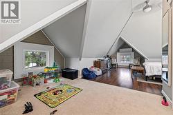Rec room with vaulted ceiling, a wall mounted AC, dark carpet, and dark wood-style flooring - 