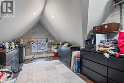 Bedroom featuring vaulted ceiling, brick wall, and dark wood finished floors - 