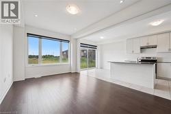 Kitchen featuring light wood-type flooring, open floor plan, under cabinet range hood, a kitchen island with sink, and electric range - 