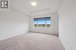 Unfurnished room featuring light colored carpet and a tray ceiling - 