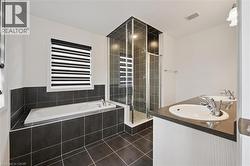 Bathroom with a bath, double vanity, a shower stall, and dark tile patterned flooring - 