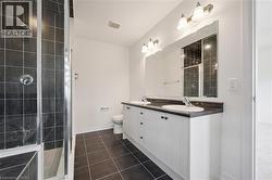 Full bath with double vanity, a shower stall, and dark tile patterned flooring - 