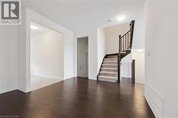 Unfurnished living room featuring stairs and hardwood / wood-style flooring - 