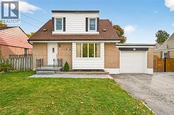 View of front of house with brick siding, driveway, a shingled roof, and an attached garage - 