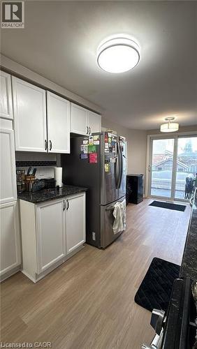 Kitchen with white cabinetry, light wood-style flooring, dark stone countertops, and freestanding refrigerator - 419 Downsview Place, Waterloo, ON - Indoor Photo Showing Kitchen