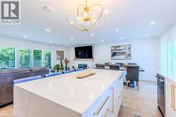 Kitchen featuring white cabinetry, open floor plan, pendant lighting, light stone counters, and recessed lighting - 