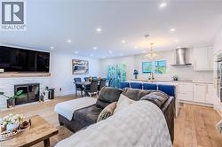 Living area with a fireplace, light wood-style floors, recessed lighting, and a chandelier - 