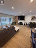 Living area with a fireplace, light wood finished floors, and recessed lighting - 