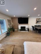 Living room with a fireplace with flush hearth, light wood-style flooring, and recessed lighting - 