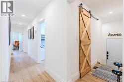 Hall with light wood-style flooring, recessed lighting, and a barn door - 