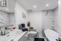 Bathroom featuring a soaking tub, light marble finish flooring, vanity, and recessed lighting - 
