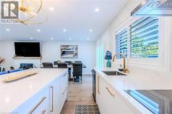 Kitchen with light stone counters, modern cabinets, white cabinetry, decorative light fixtures, and recessed lighting - 