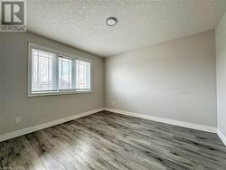 Unfurnished room with baseboards, a textured ceiling, visible vents, and wood finished floors - 