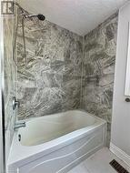 Full bathroom featuring shower / bath combination, marble finish floor, a textured ceiling, and visible vents - 
