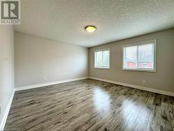 Spare room featuring baseboards, a textured ceiling, and wood finished floors - 
