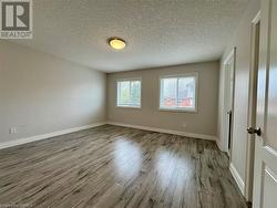 Empty room with a textured ceiling, baseboards, and wood finished floors - 