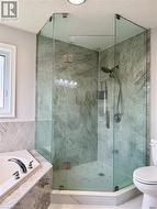 Full bath featuring toilet, a textured ceiling, a shower stall, and a garden tub - 