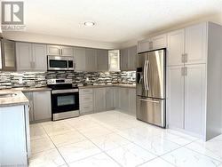 Kitchen featuring marble finish floor, gray cabinets, appliances with stainless steel finishes, and a textured ceiling - 