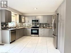 Kitchen featuring marble finish floor, gray cabinets, and stainless steel appliances - 