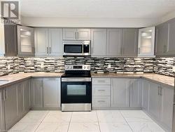 Kitchen with stainless steel appliances, a textured ceiling, gray cabinetry, and marble finish floor - 