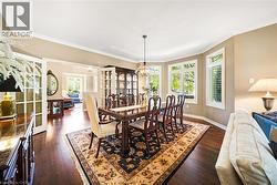 Dining room featuring dark wood-type flooring, ornamental molding, a chandelier, and french doors - 