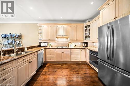 Kitchen with stainless steel appliances, light stone countertops, dark wood-style flooring, glass insert cabinets, and recessed lighting - 4165 Stonebridge Crescent, Burlington, ON - Indoor Photo Showing Kitchen With Double Sink