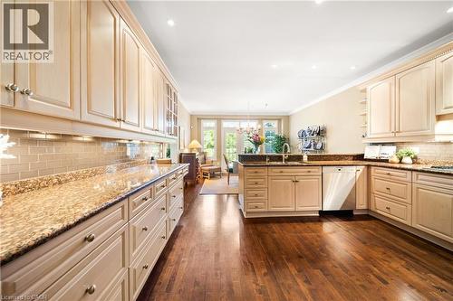 Kitchen with tasteful backsplash, dark stone countertops, a chandelier, a peninsula, and dishwasher - 4165 Stonebridge Crescent, Burlington, ON - Indoor Photo Showing Kitchen With Upgraded Kitchen