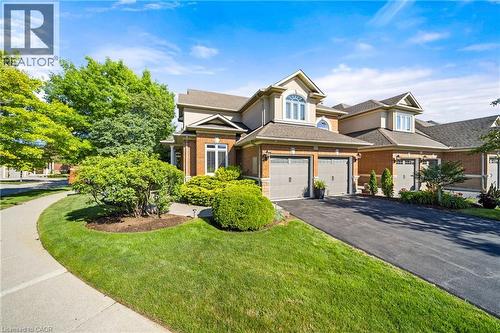 View of front facade featuring brick siding, asphalt driveway, a garage, a front lawn, and stucco siding - 4165 Stonebridge Crescent, Burlington, ON - Outdoor With Facade
