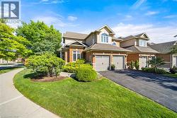 View of front facade featuring brick siding, asphalt driveway, a garage, a front lawn, and stucco siding - 