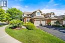 View of front facade featuring brick siding, asphalt driveway, a garage, a front lawn, and stucco siding - 4165 Stonebridge Crescent, Burlington, ON  - Outdoor With Facade 