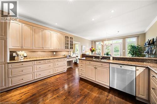 Kitchen with dishwasher, glass insert cabinets, dark stone countertops, dark wood-type flooring, and crown molding - 4165 Stonebridge Crescent, Burlington, ON - Indoor Photo Showing Kitchen
