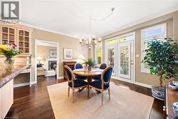 Dining area featuring a warm lit fireplace, crown molding, dark wood-style floors, and a chandelier - 