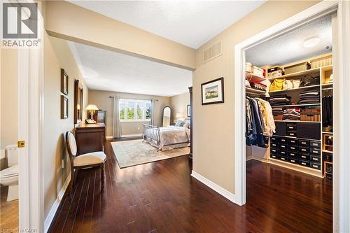 Bedroom with a walk in closet, dark wood finished floors, and a textured ceiling - 4165 Stonebridge Crescent, Burlington, ON - Indoor