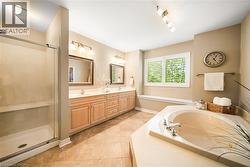 Full bath with double vanity, a garden tub, a shower stall, and light tile patterned floors - 