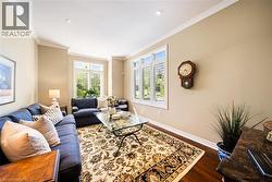 Living area with dark wood-style flooring, crown molding, and recessed lighting - 