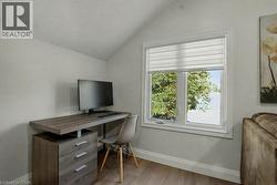Office area featuring vaulted ceiling, light wood-style floors, and a textured ceiling - 