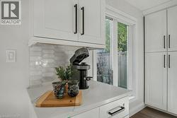 Kitchen view of backsplash, white cabinets, and dark wood-style flooring - 
