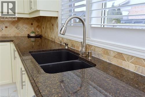 Kitchen view of tasteful backsplash, dark stone counters, and white cabinets - 5109 Blue Spruce Avenue, Burlington, ON - Indoor Photo Showing Kitchen With Double Sink