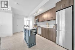 Kitchen featuring appliances with stainless steel finishes, a center island, backsplash, and light wood-style floors - 