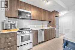 Kitchen featuring appliances with stainless steel finishes, tasteful backsplash, light stone countertops, modern cabinets, and light wood-style floors - 