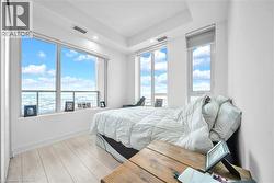 Bedroom featuring light wood finished floors and multiple windows - 