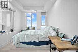 Bedroom with light wood-type flooring and a raised ceiling - 