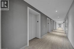 Hallway with elevator, light colored carpet, and recessed lighting - 