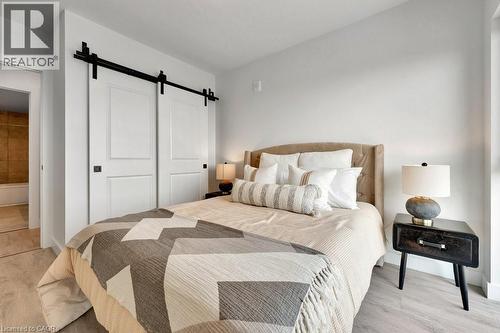 Bedroom with a barn door, light wood-style floors, and a closet - 15 Glebe Street Unit# 1511, Cambridge, ON - Indoor Photo Showing Bedroom
