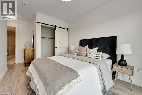 Bedroom featuring a barn door, light wood-style floors, and a closet - 15 Glebe Street Unit# 1511, Cambridge, ON - Indoor Photo Showing Bedroom