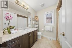 Bathroom with curtained shower, vanity, and light tile patterned floors - 