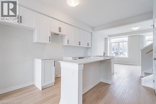Kitchen featuring white cabinetry, light wood-type flooring, and a peninsula - 155 Equestrian Way Unit# 22, Cambridge, ON - Indoor