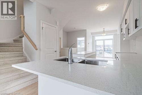 Kitchen with a peninsula, light stone counters, white cabinetry, and light wood finished floors - 155 Equestrian Way Unit# 22, Cambridge, ON - Indoor Photo Showing Kitchen