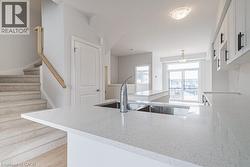Kitchen with a peninsula, light stone counters, white cabinetry, and light wood finished floors - 