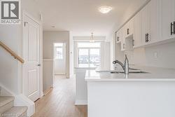 Kitchen with light wood-type flooring, white cabinets, light stone countertops, and a peninsula - 